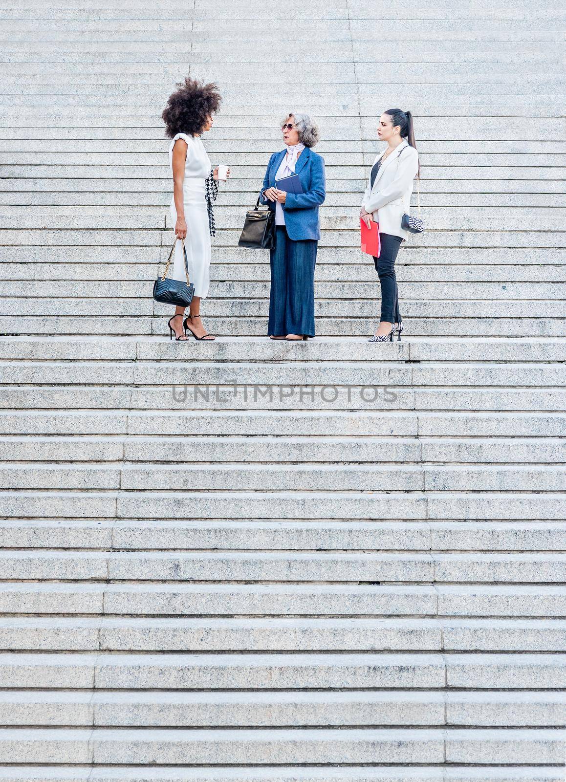 co-workers talking in the middle of a granite staircase by ivanmoreno