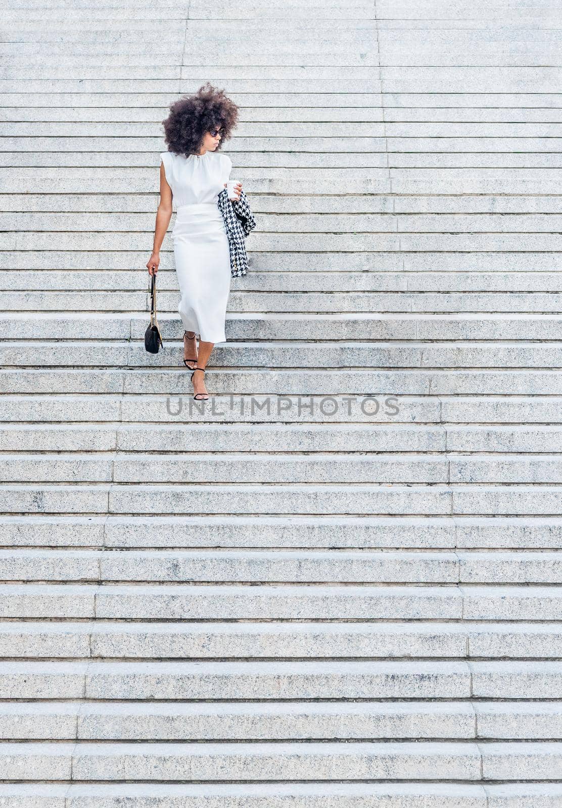 black woman alone walking down the stairs looking to the side in a white dress