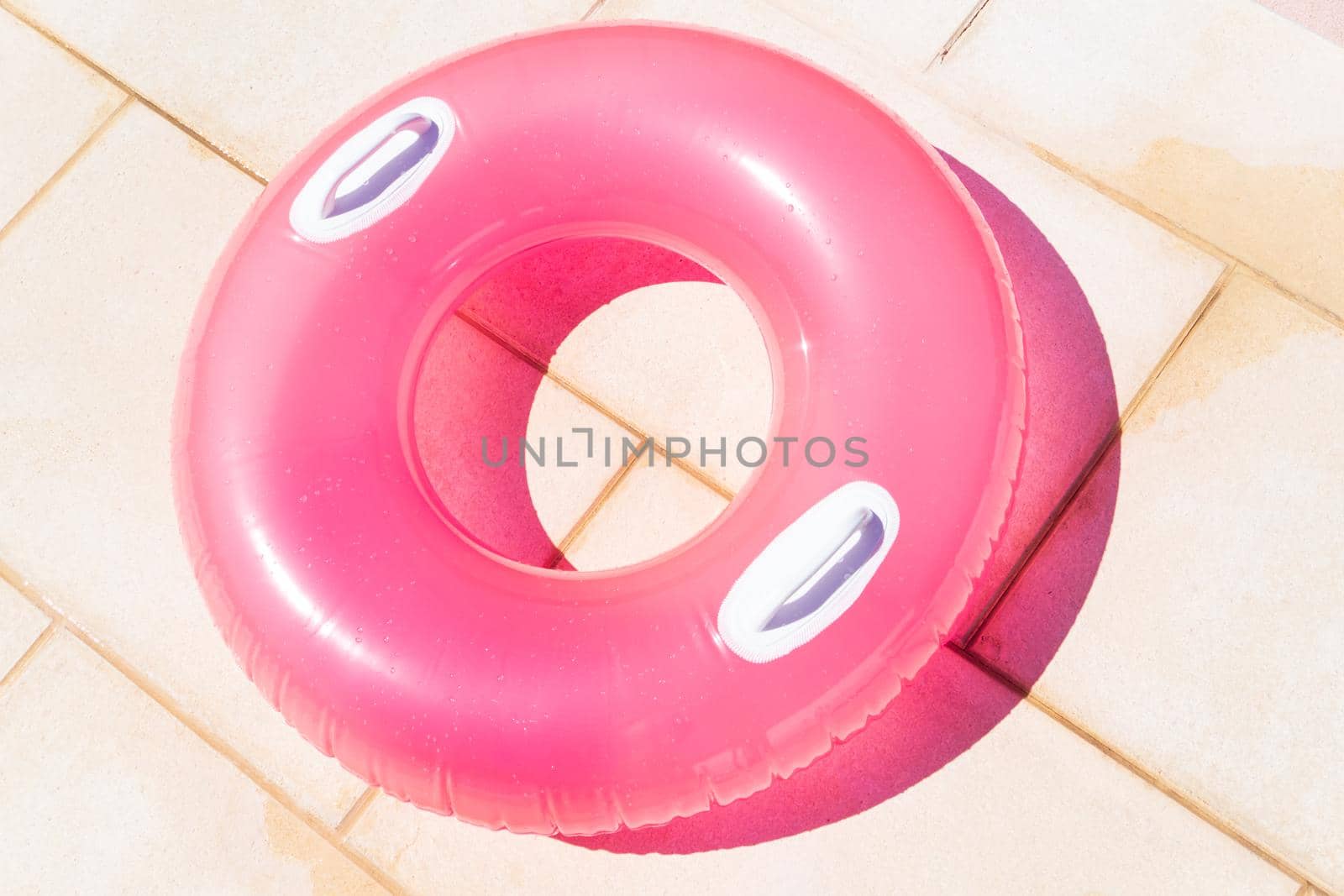 Translucent pink swim ring under the bright sun background