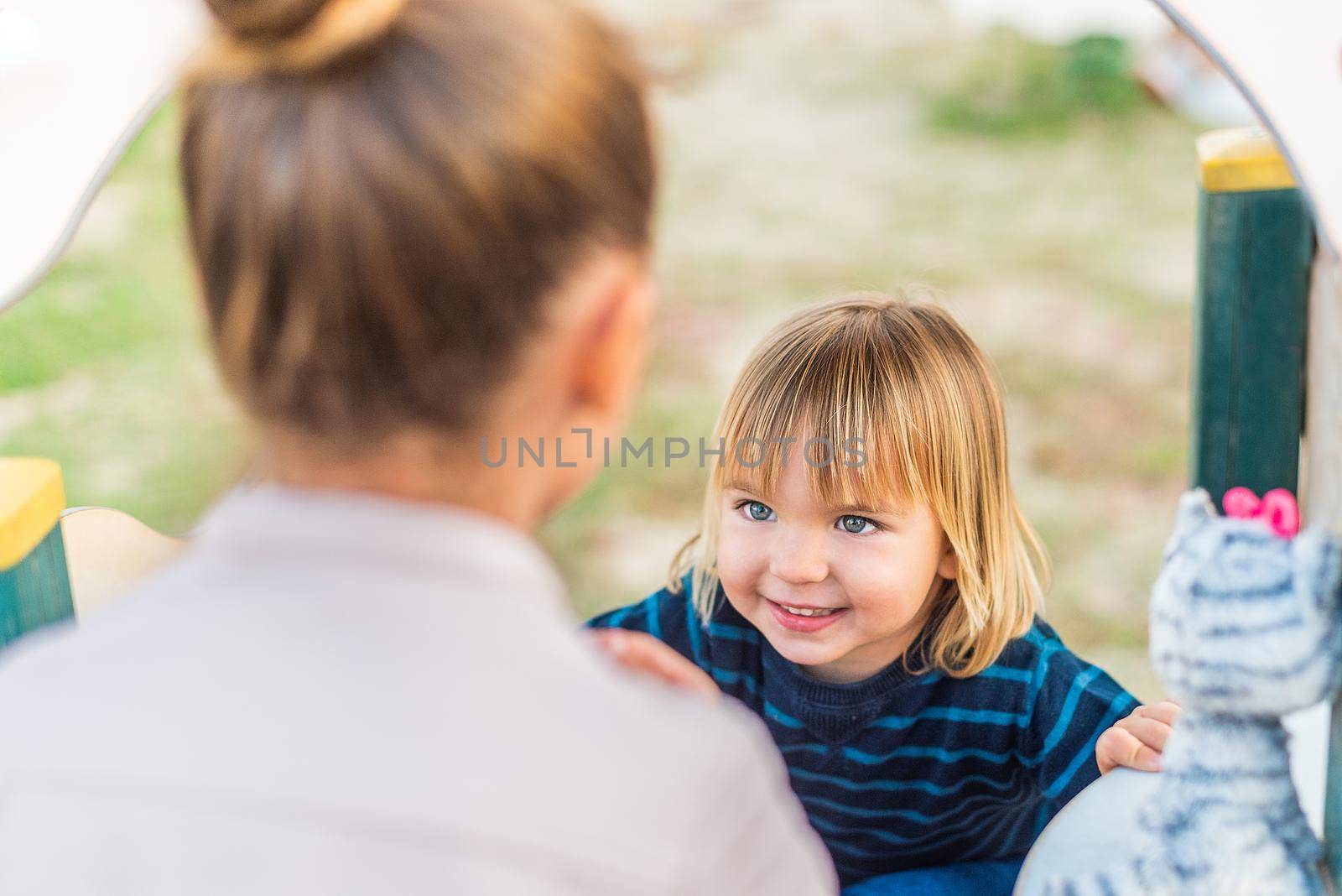 A little boy looking at his sister on the playground. by ivanmoreno