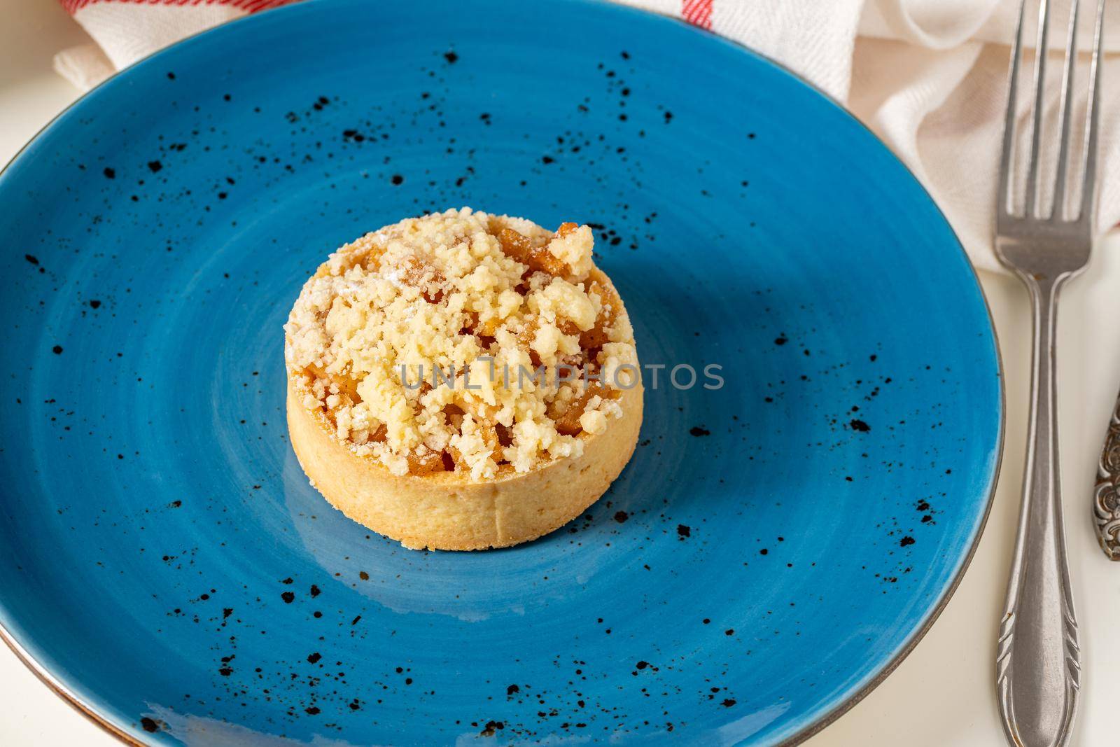 Freshly baked single portion apple pie on a blue porcelain plate