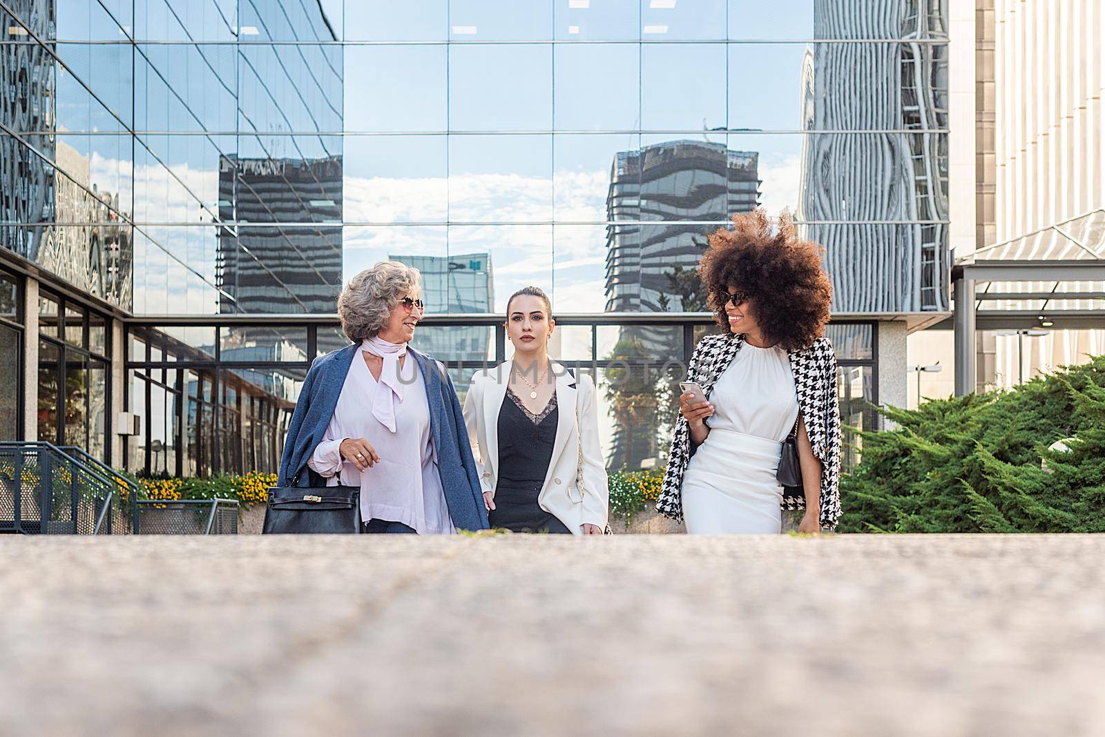 three business women leaving work talking to each other, front view