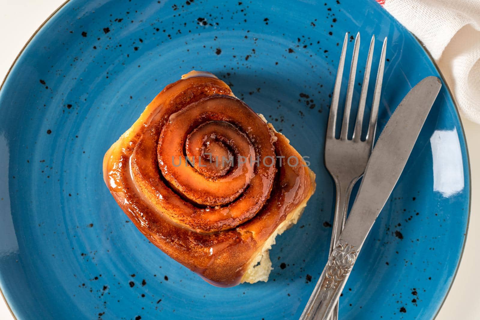 Freshly baked cinnamon roll on a blue porcelain plate
