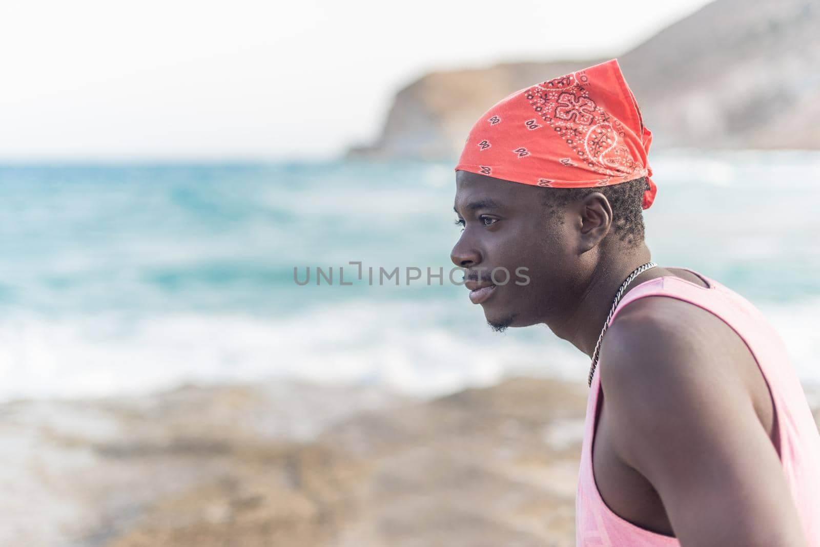 black man looking at the sea enjoying the good weather, horizontal blurred background
