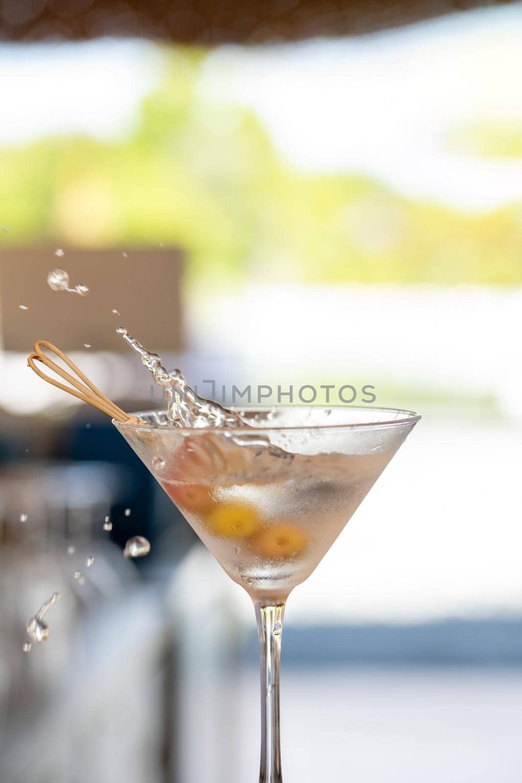 margarita cocktail in the bar. martini glass of cocktail with olives on blurry background