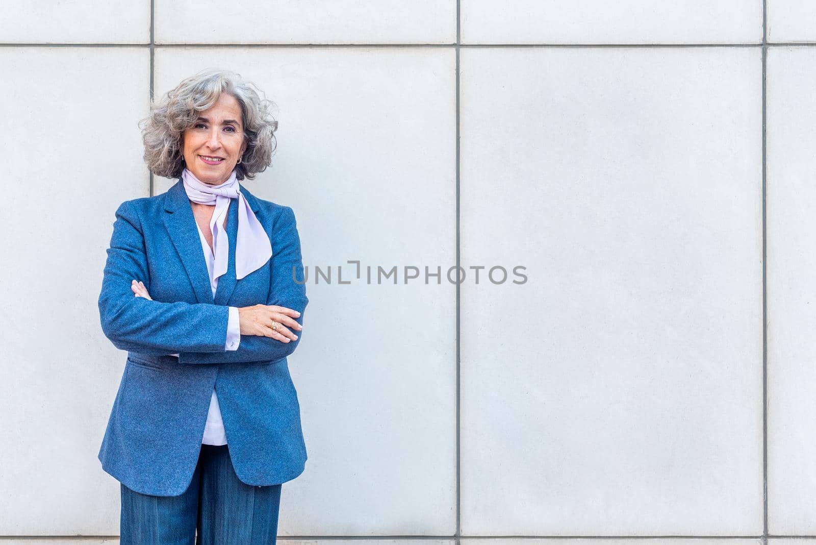 mature woman in a blue suit and a scarf, looking at camera