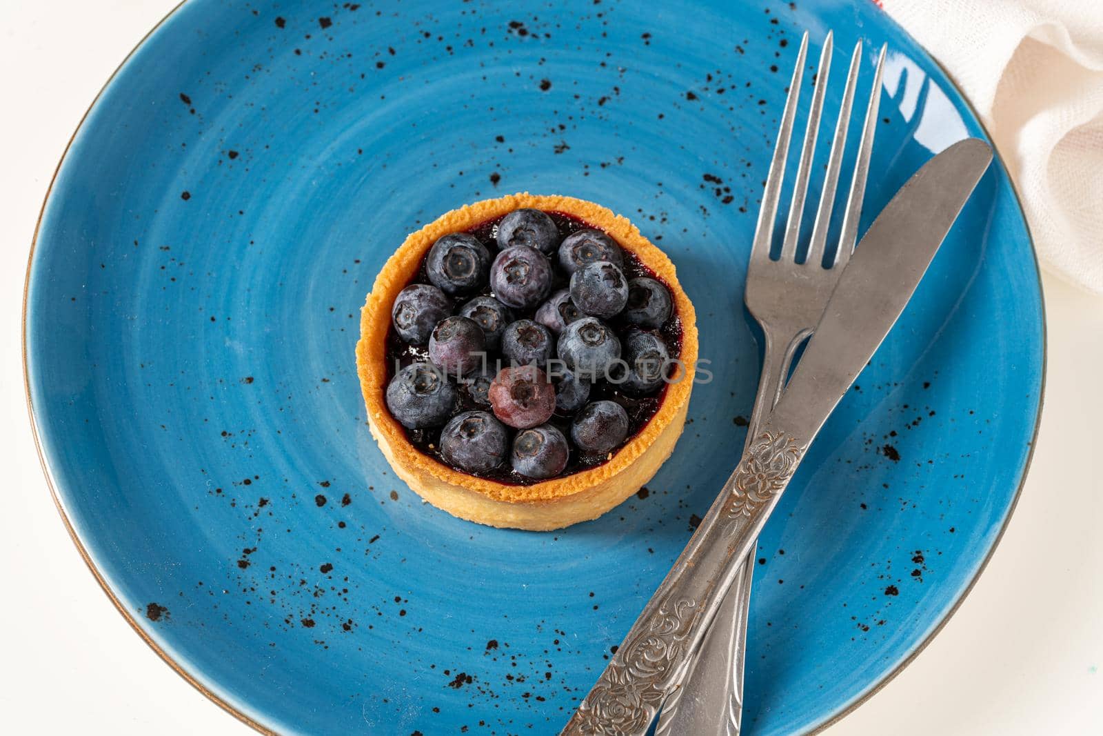 Freshly baked blueberry tart on a blue porcelain plate