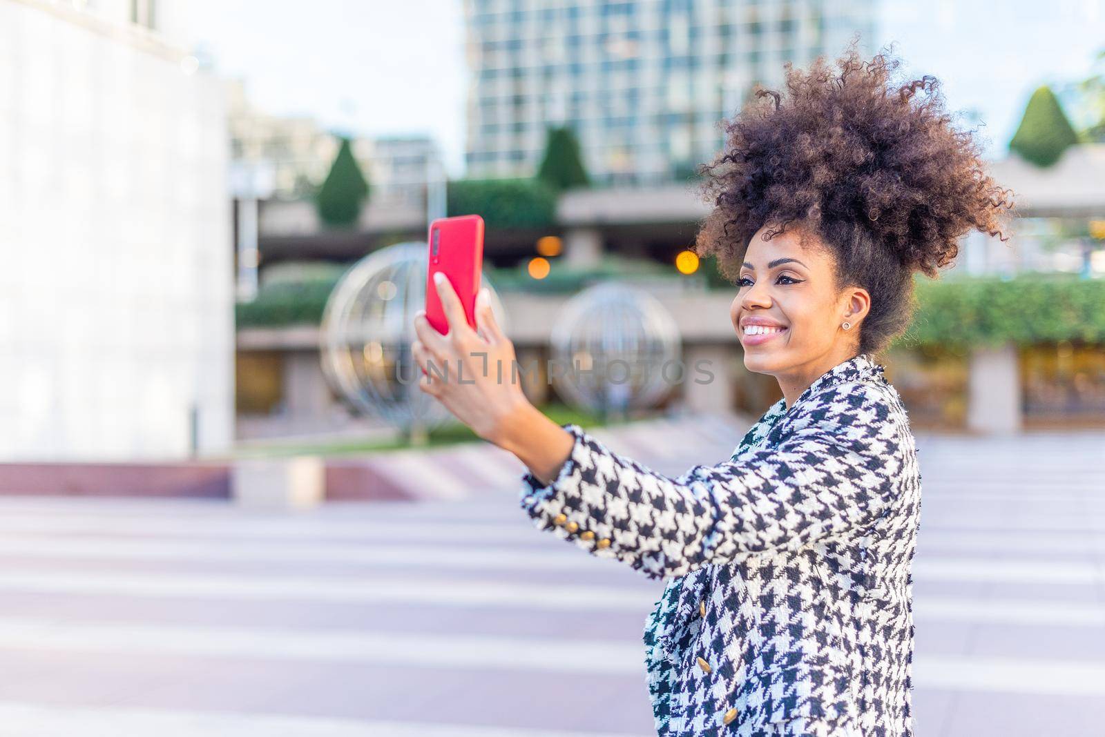black woman taking a selfie smiling with a mobile phone by ivanmoreno
