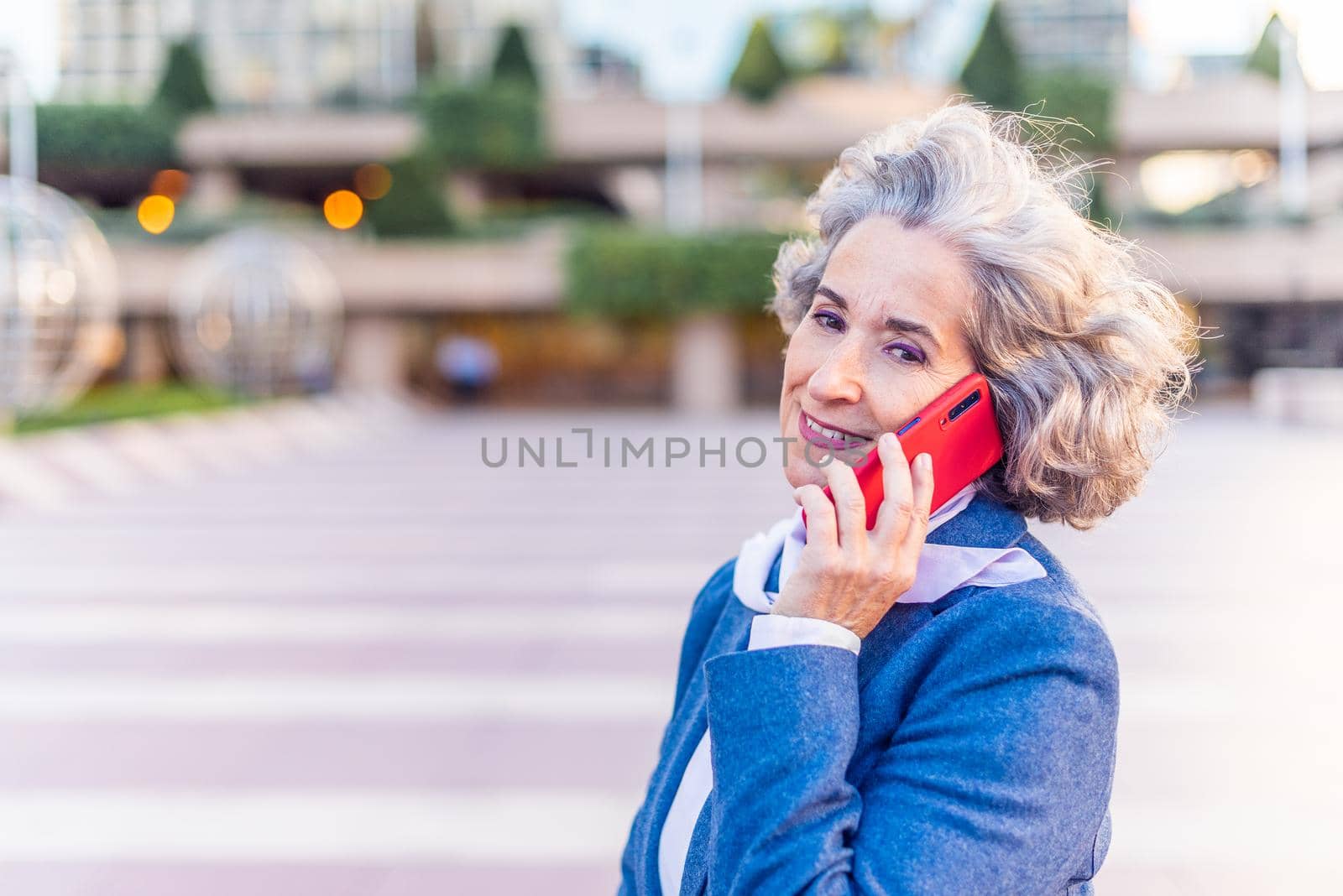 mature businesswoman smiling at the camera while attending to a customer on the phone