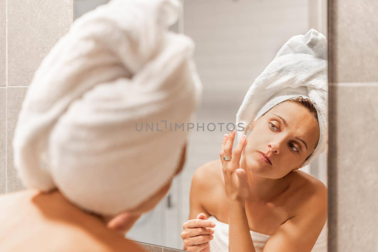 Focus caucasian adult woman applying moisturizing skin care cream after a shower at a hotel. Concept of skin care.