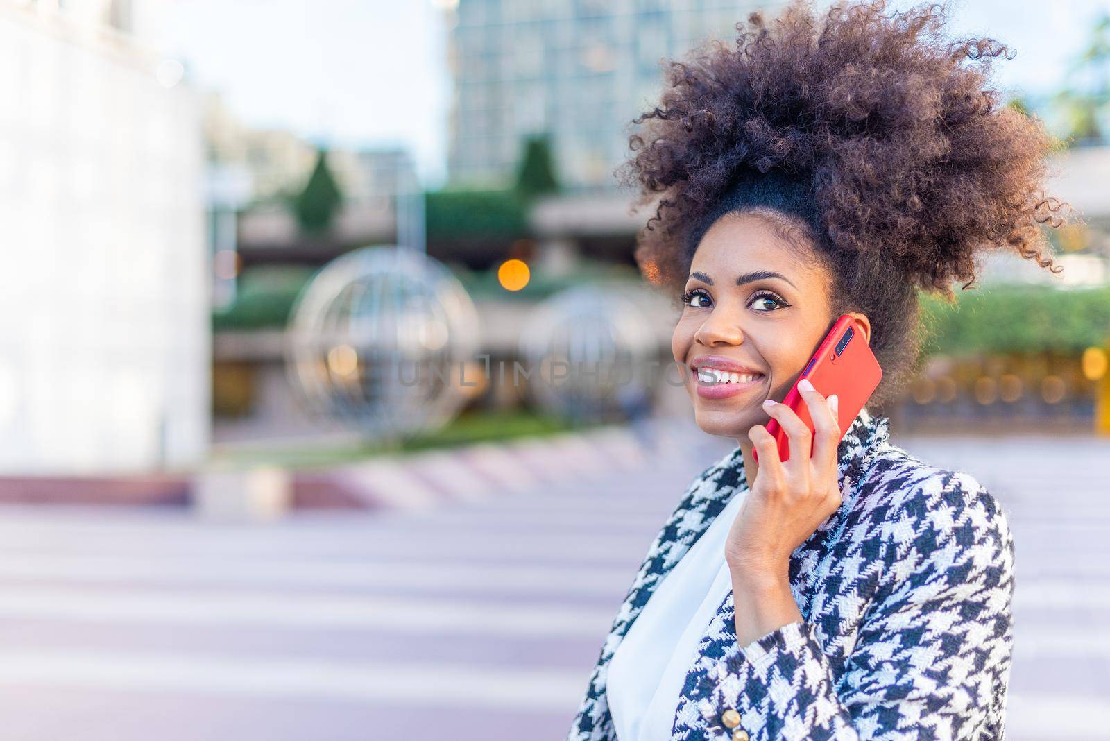 adult woman with tall afro hair listening to her caller on the phone, horizontal portrait