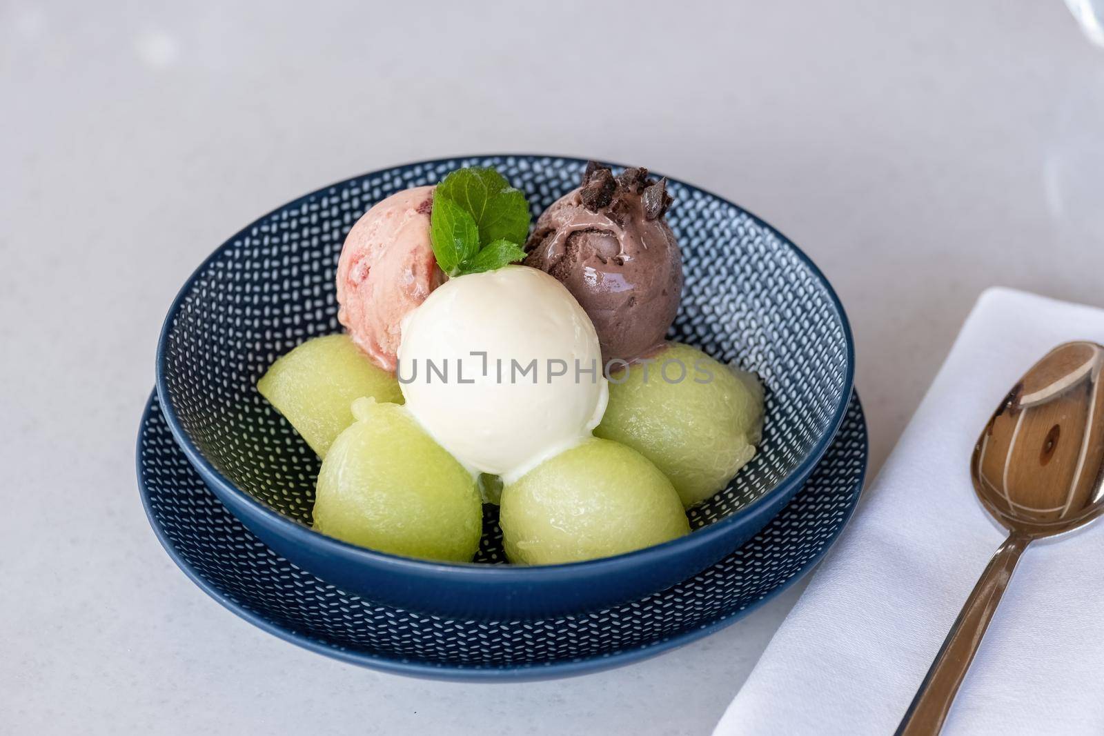 Fruit ice cream on melon balls on marble table by Sonat