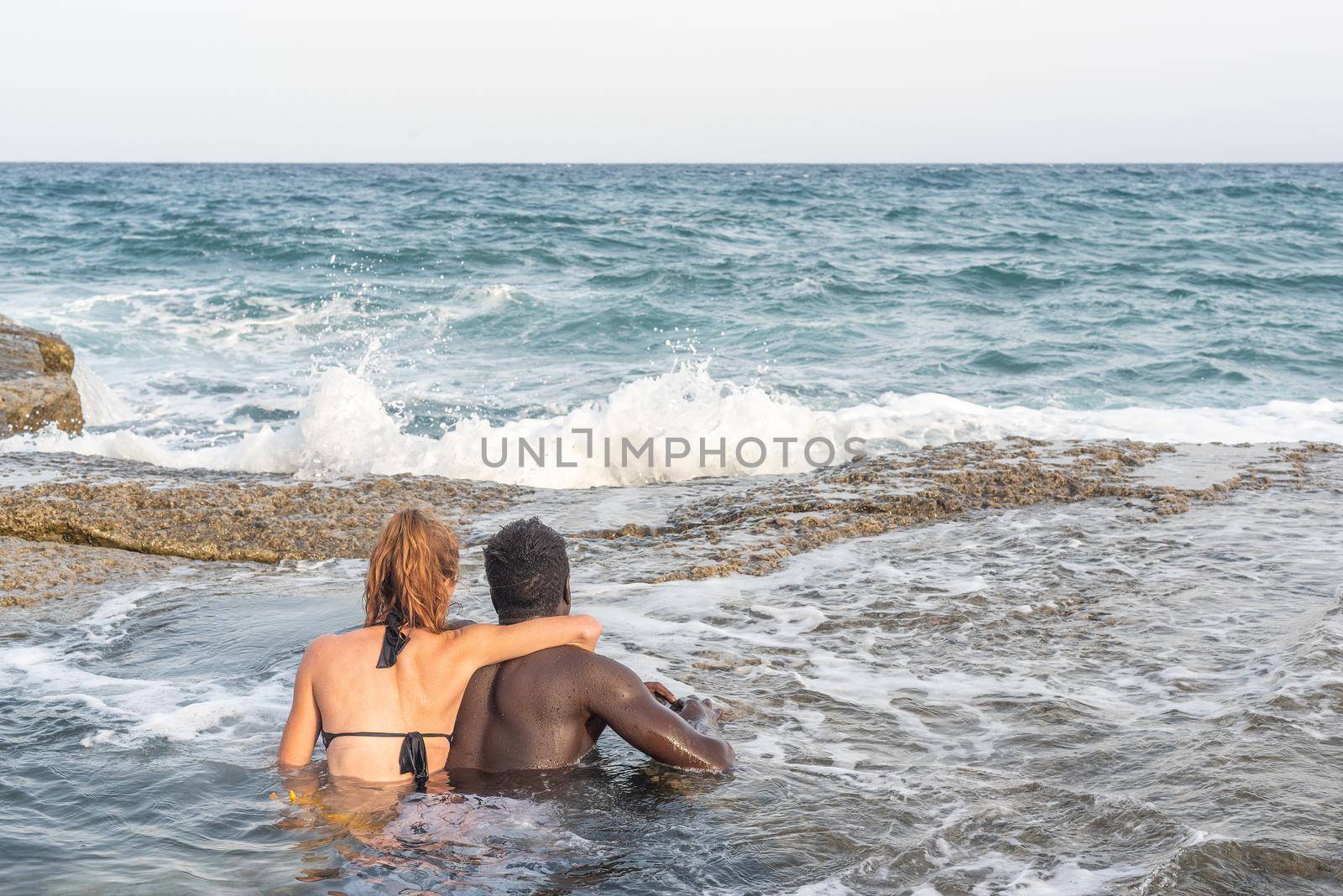 couple bathing in the sea embracing each other looking at the horizon, sea on the background