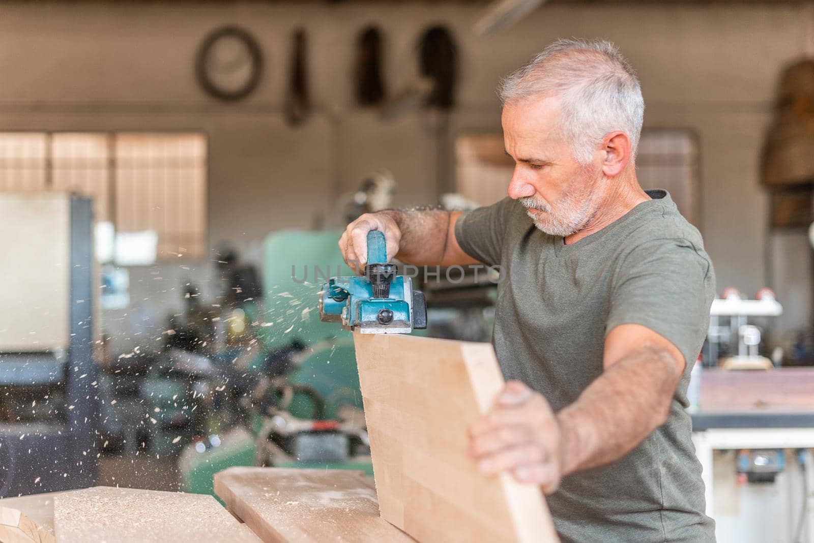 Man planing wood with a hand planer, flying sawdust by ivanmoreno