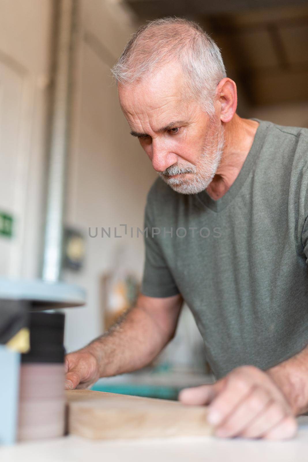 One focused person sanding the edge of a wooden step, vertical