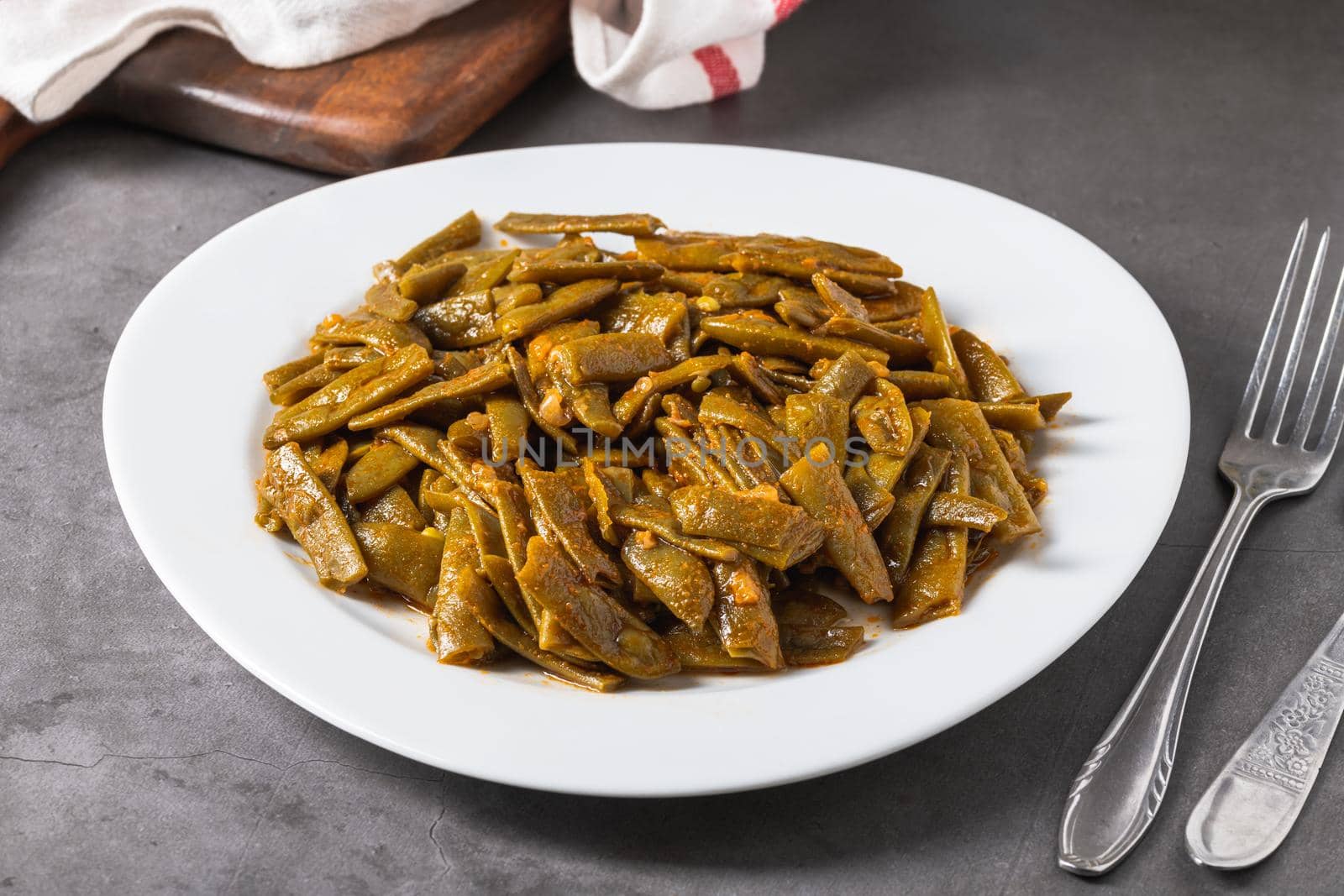 Green beans with olive oil on a white porcelain plate. Healthy eating concept