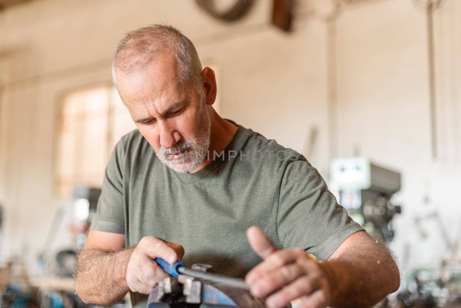 Male person filing a metal tool. Carpentry by ivanmoreno