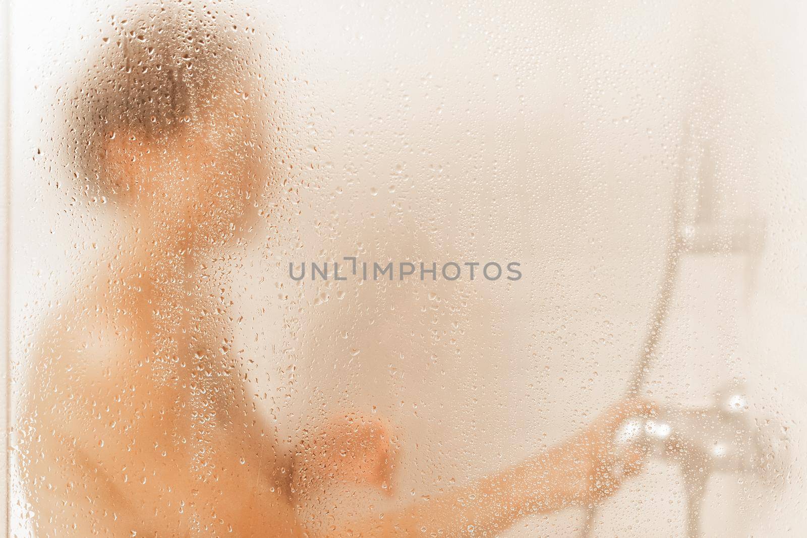 Unrecognizable woman taking a shower in a hotel by ivanmoreno