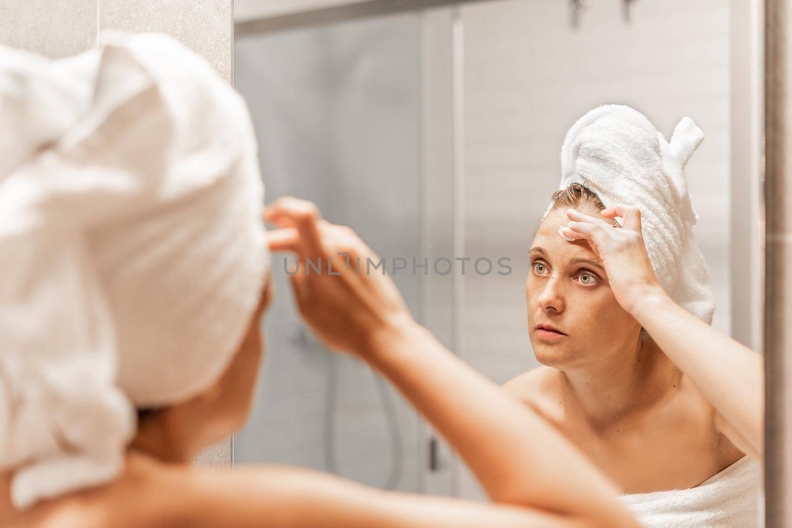 Adult woman applying moisturizing skin care cream on forehead. by ivanmoreno
