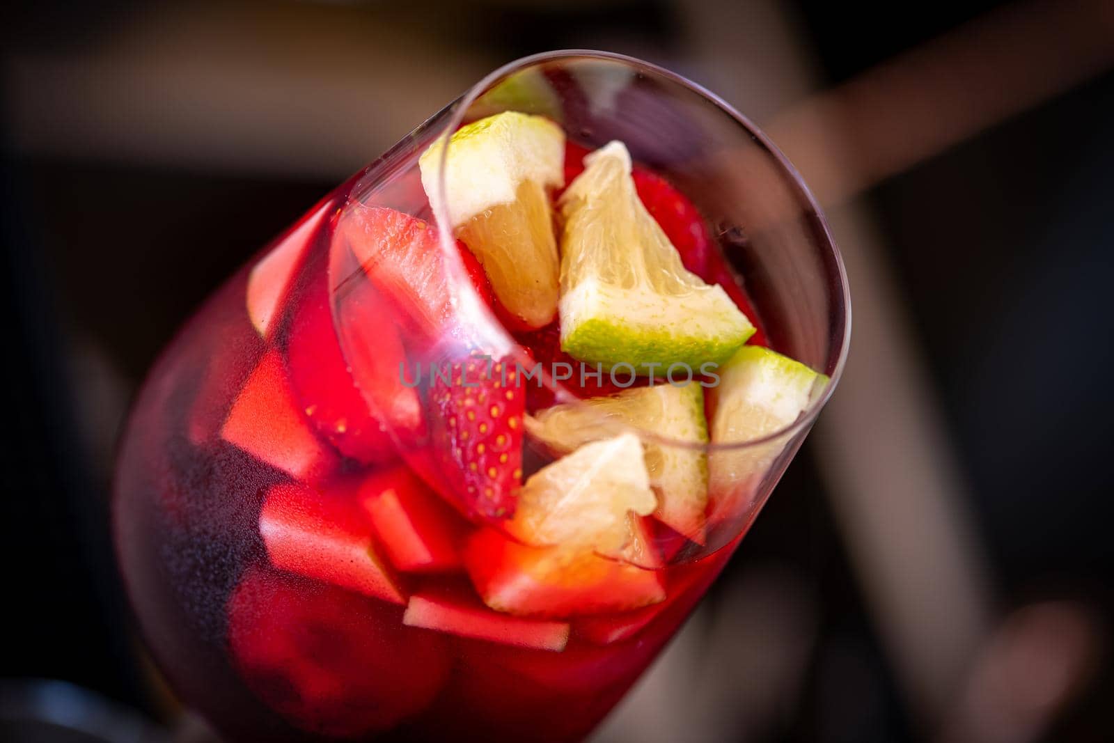 Glass of red Sangria and fruits on dark stone table