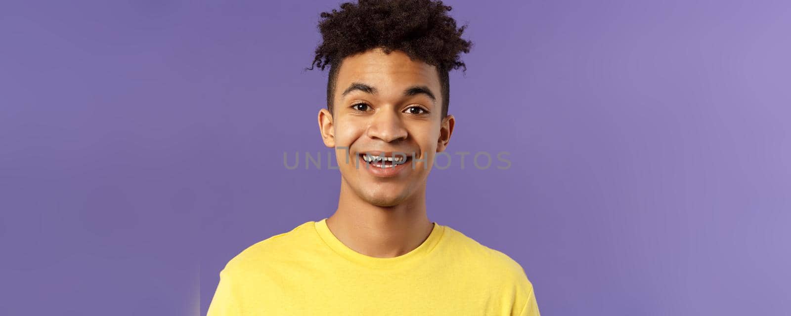 Close-up portrait of cheerful smiling man looking happy, express enthusiastic optimistic emotions, seeing something pleasant and interesting, standing purple background.