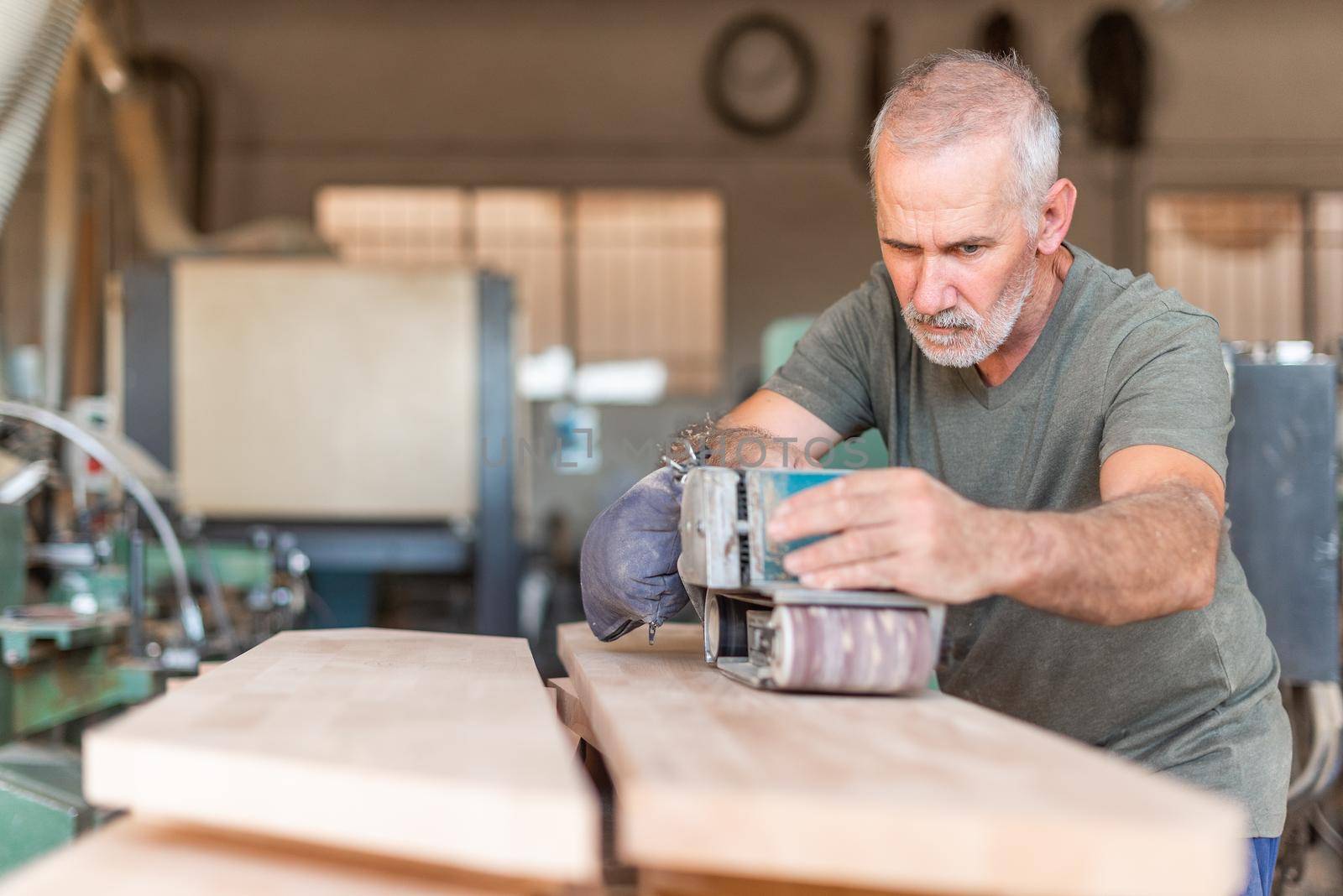 Male person focused working with a hand sander by ivanmoreno