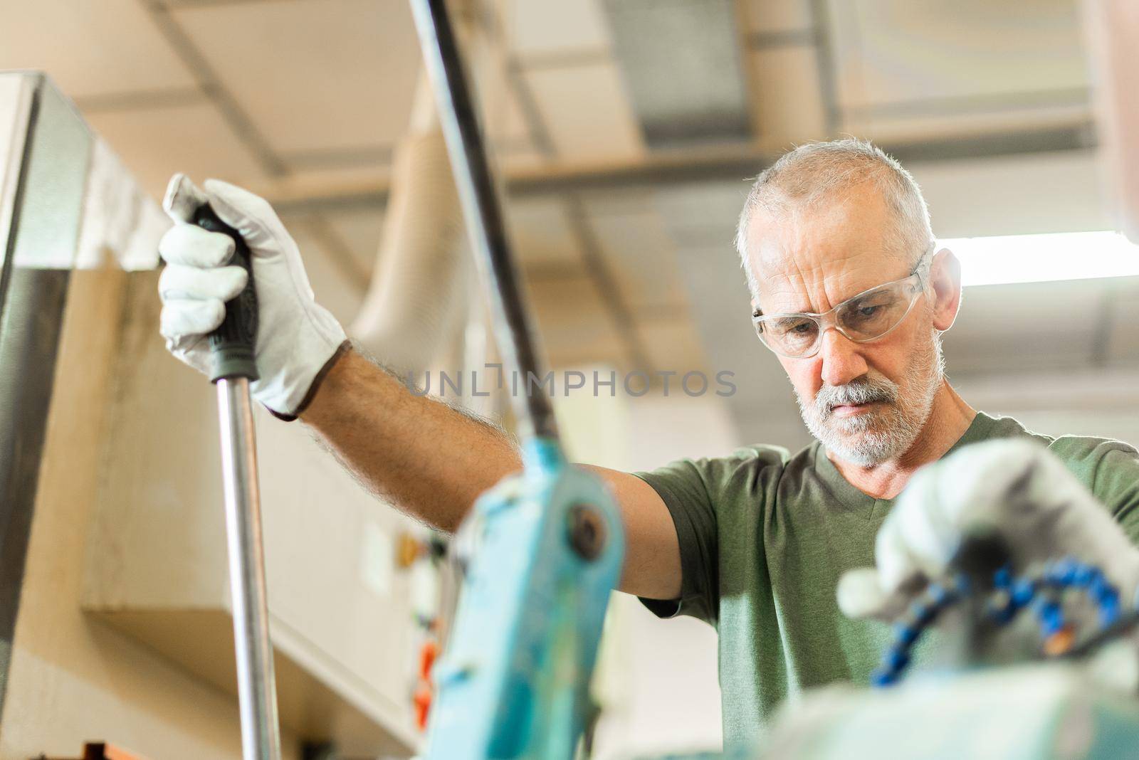 Older worker threading a steel bar in an industrial factory, horizontal background