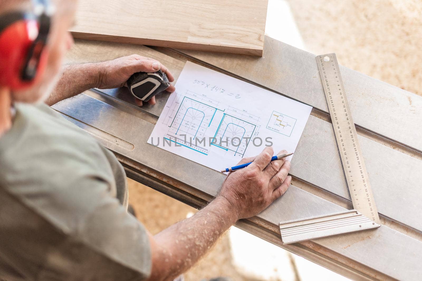 person drawing on a wooden board with tape measure and ruler, horizontal top view