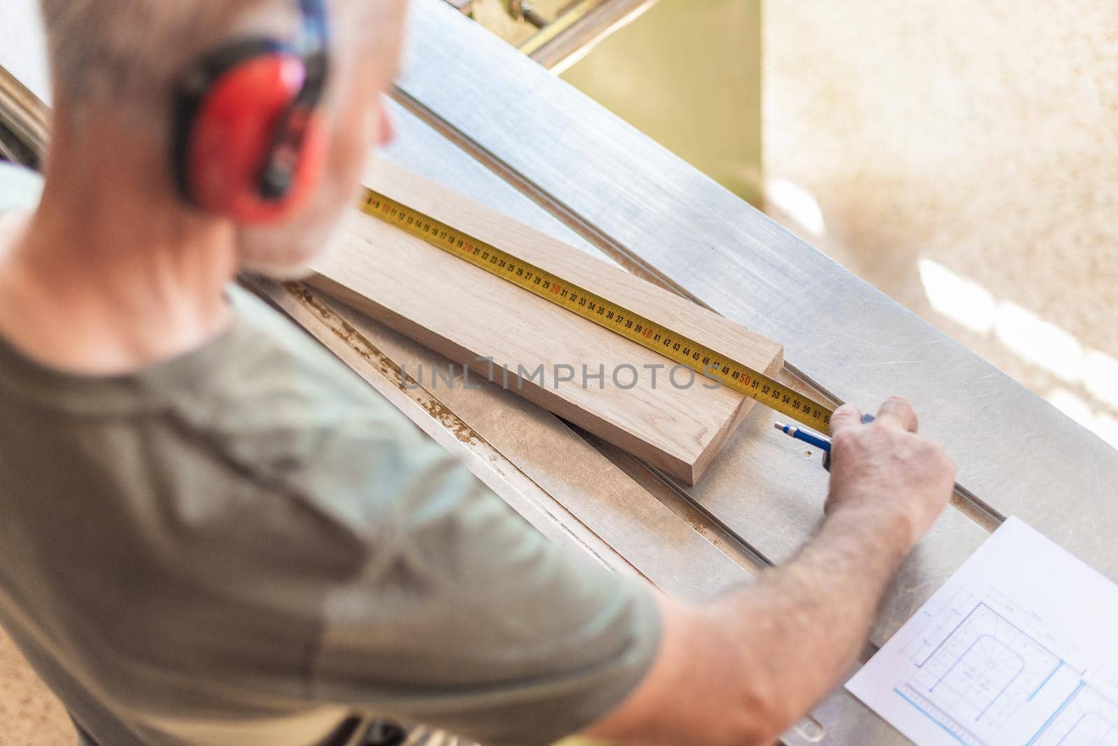 top view of a man measuring a board of wood on a sliding table