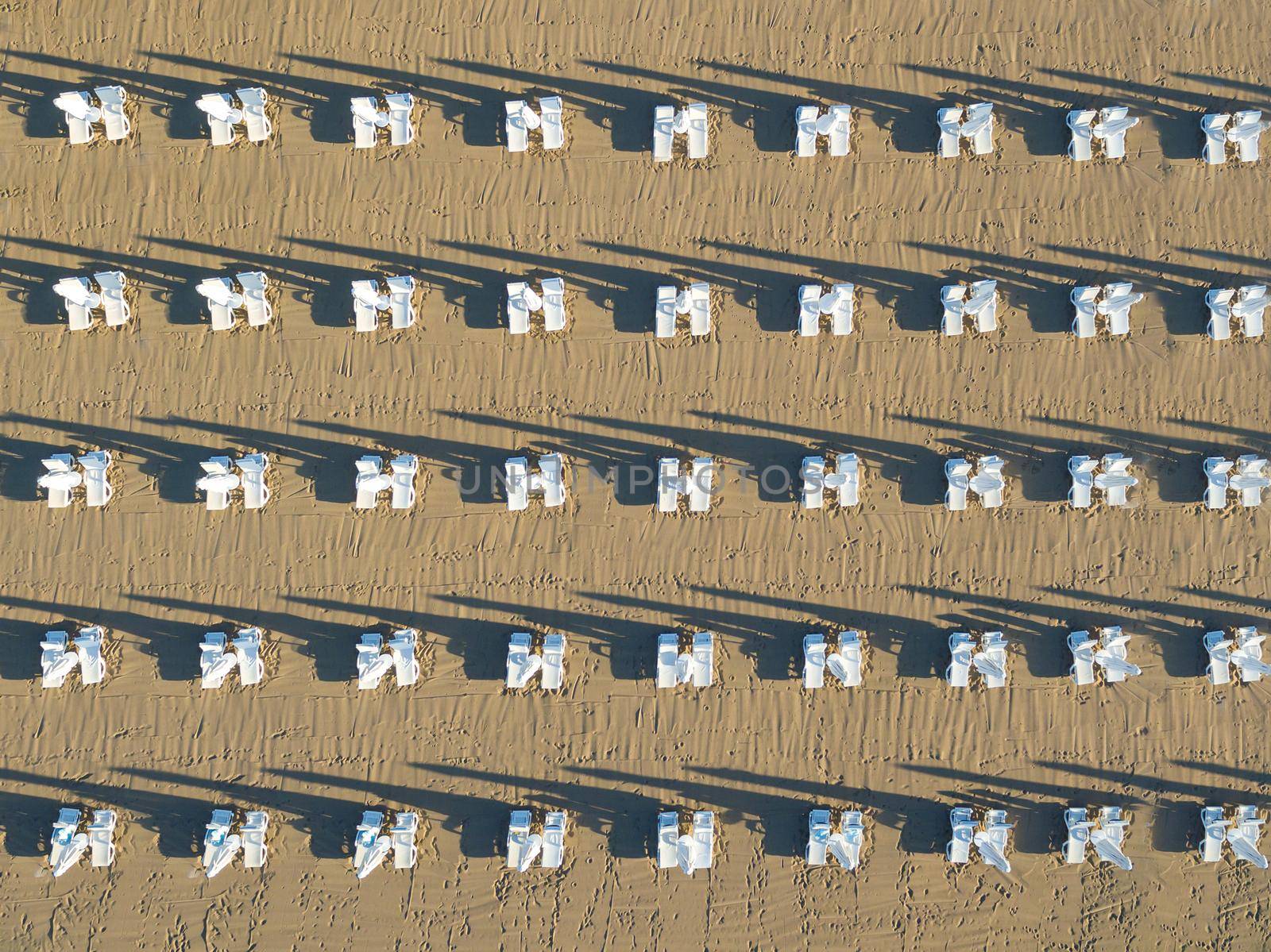Sunbeds and umbrellas lined up on the beach at sunrise