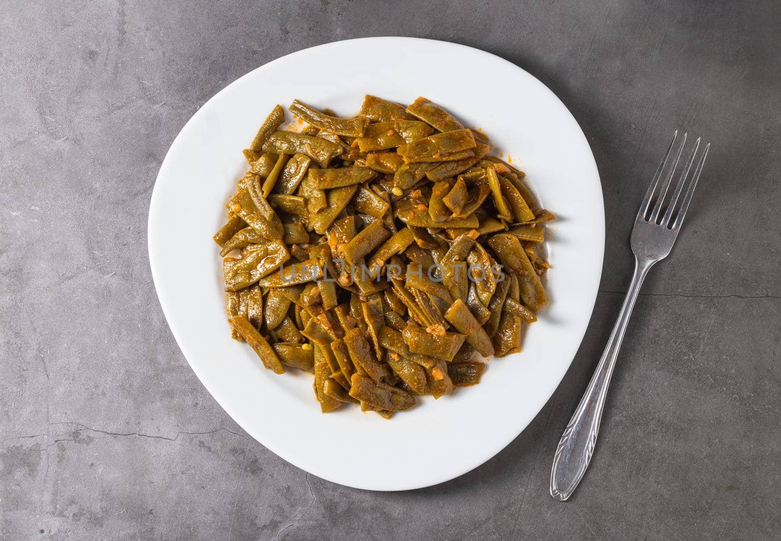 Green beans with olive oil on a white porcelain plate. Healthy eating concept