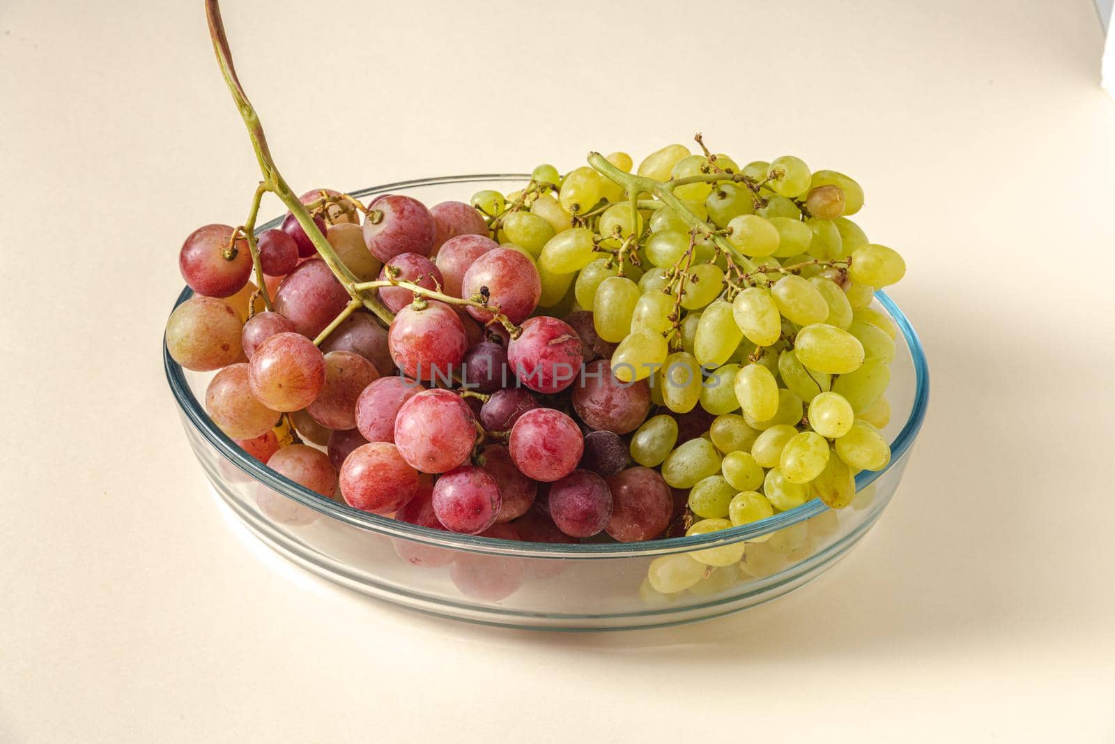 Fresh red and green grapes in a glass bowl. Healthy eating concept by Sonat