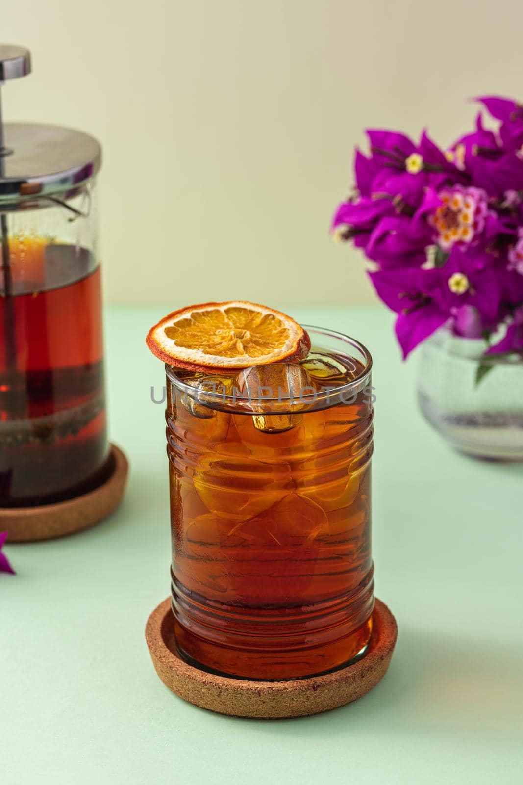 Freshly brewed iced red fruit tea on green table