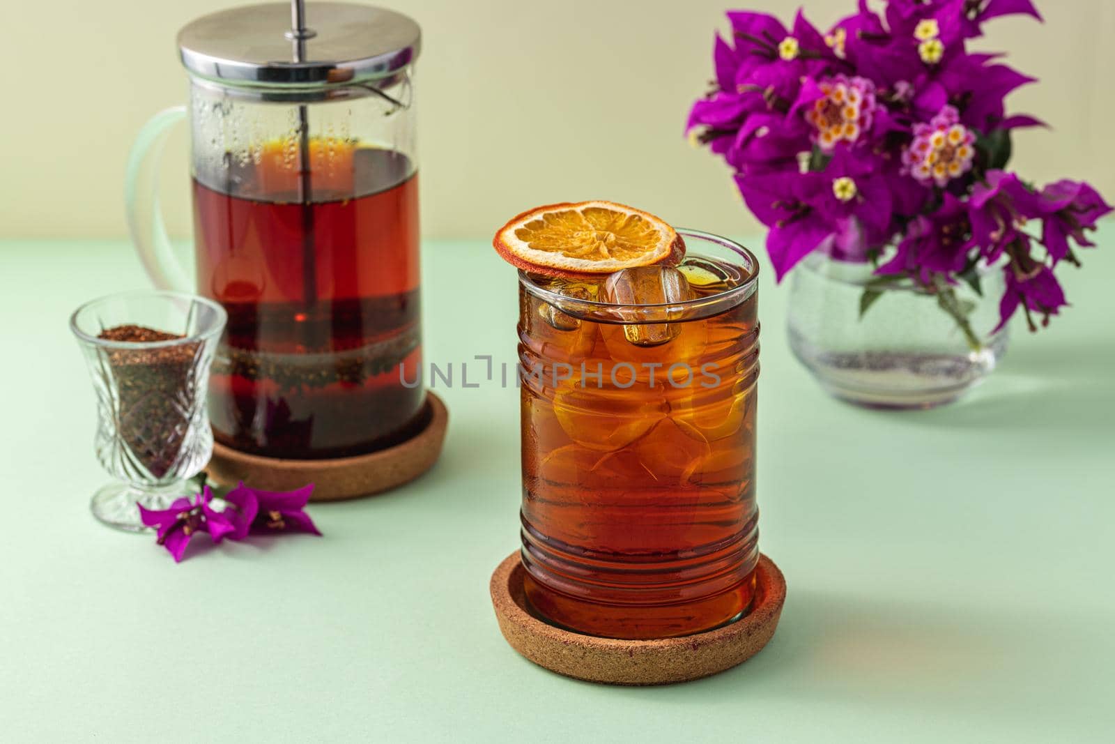 Freshly brewed iced red fruit tea on green table by Sonat
