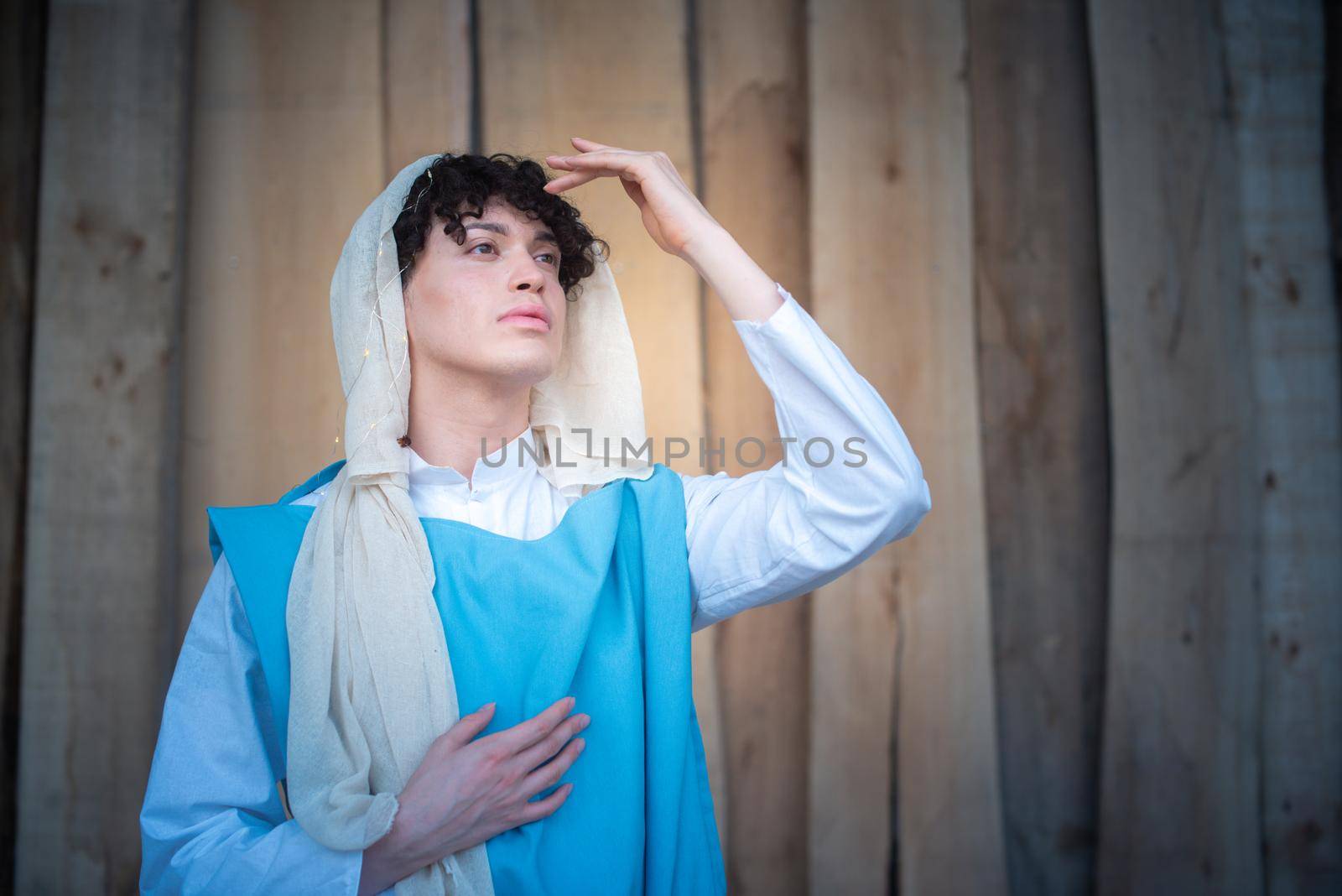 Portrait of an androgynous virgin mary gesturing while praying and gazing at the horizon