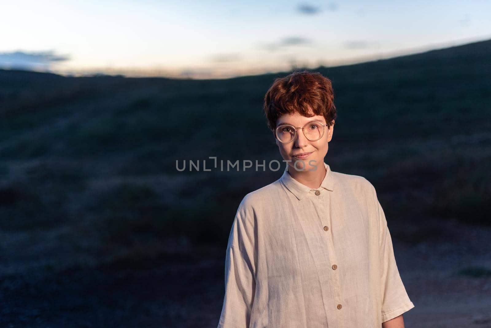 Portrait with copy space at dusk of a non-binary gender woman looking at the camera outside