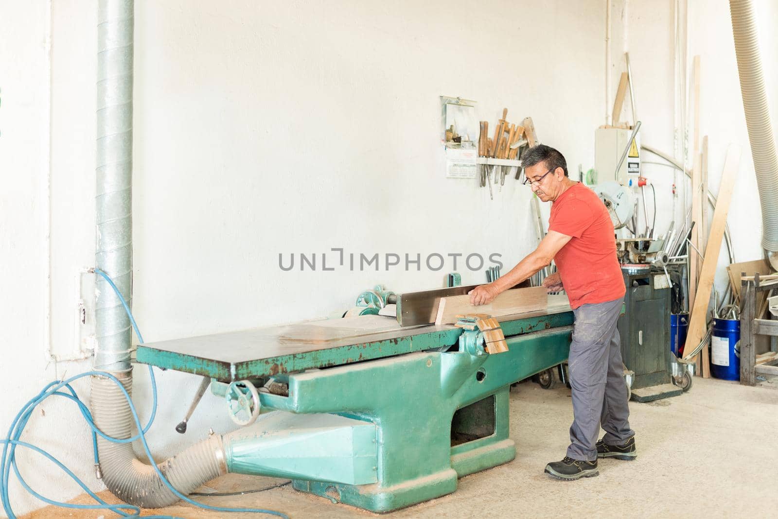 Adult male working manually with a wood planing machine by ivanmoreno