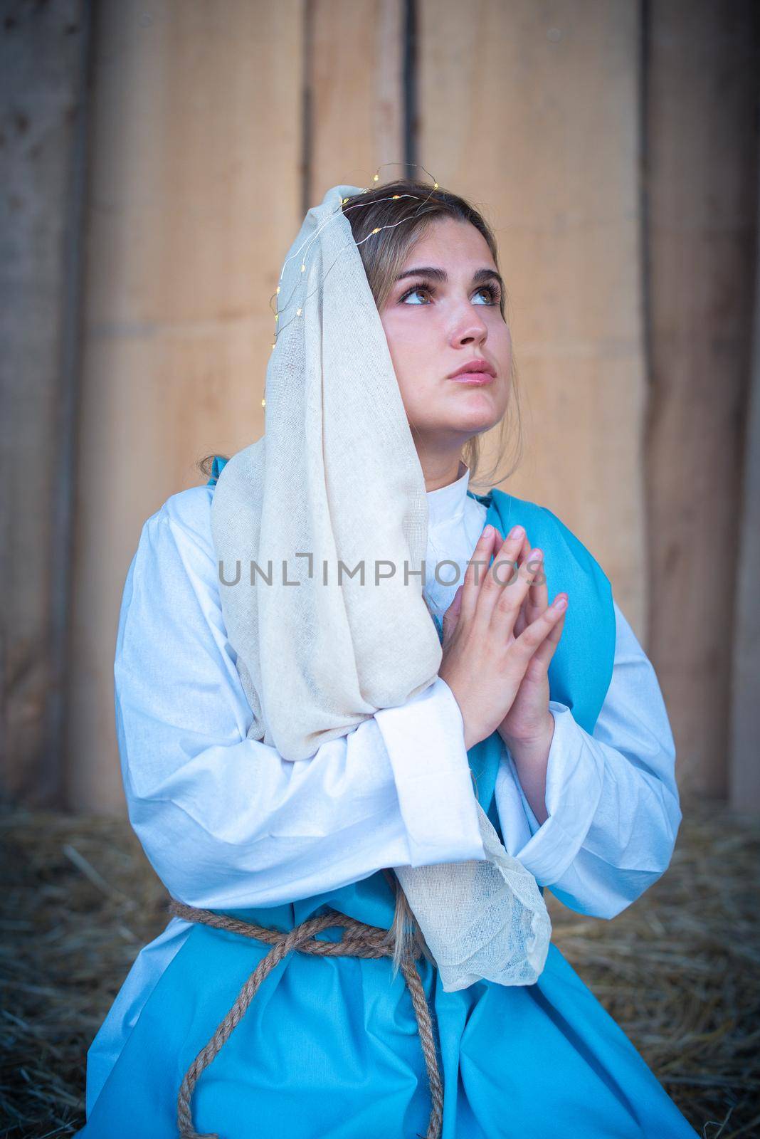 Caucasian woman representing virgin mary while praying in a crib by ivanmoreno