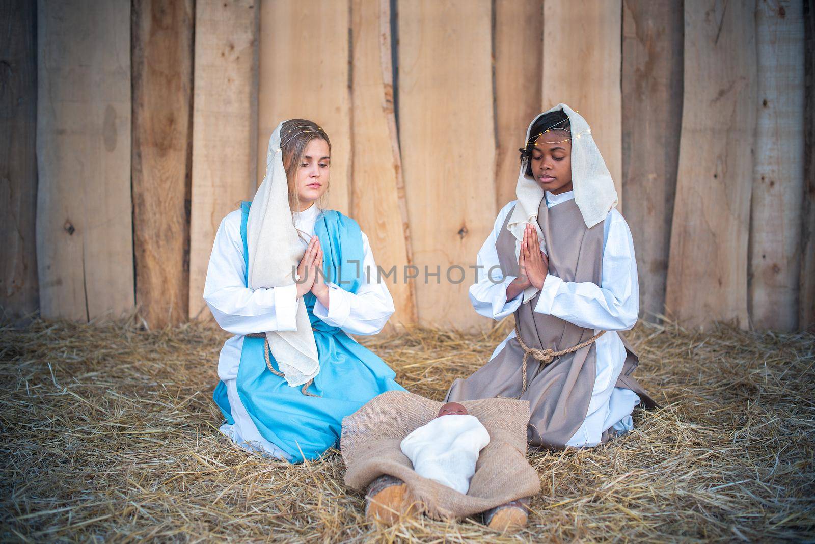 Lgtb nativity with two virgin marys praying next to a black representation of Jesus baby in a crib