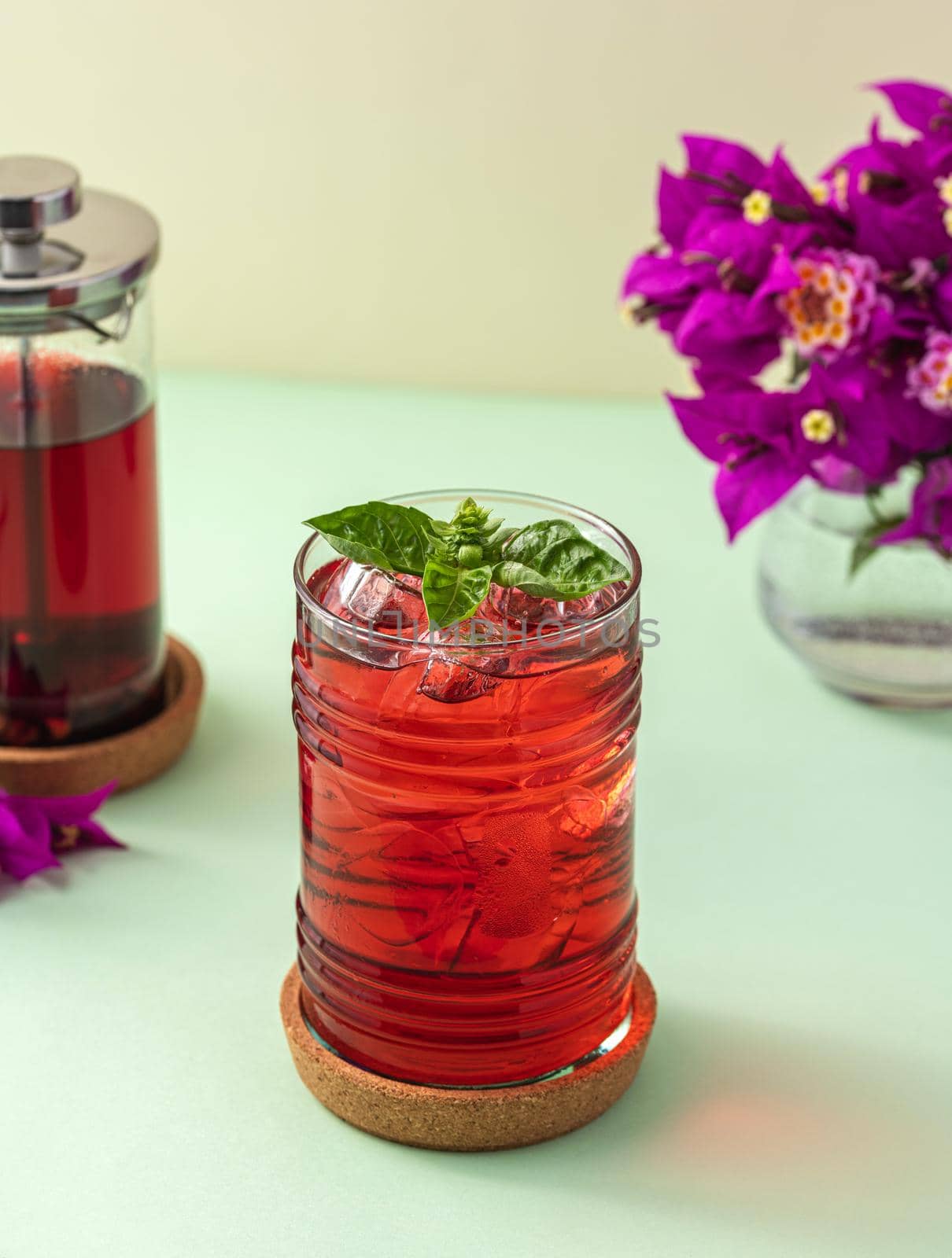 Freshly brewed iced red fruit tea on green table by Sonat