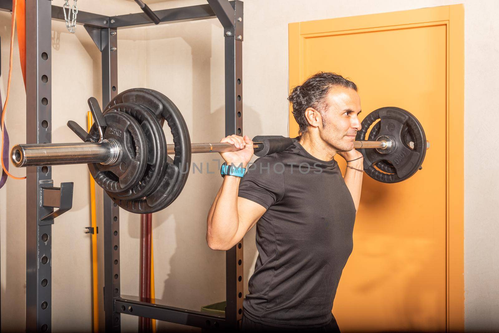 Close up of athlete man doing squats with bar at gym. Concept of exercise in the gym.