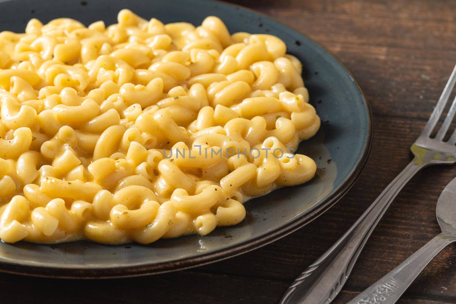 Delicious Mac n Cheese or macaroni and cheese on a black porcelain plate by Sonat