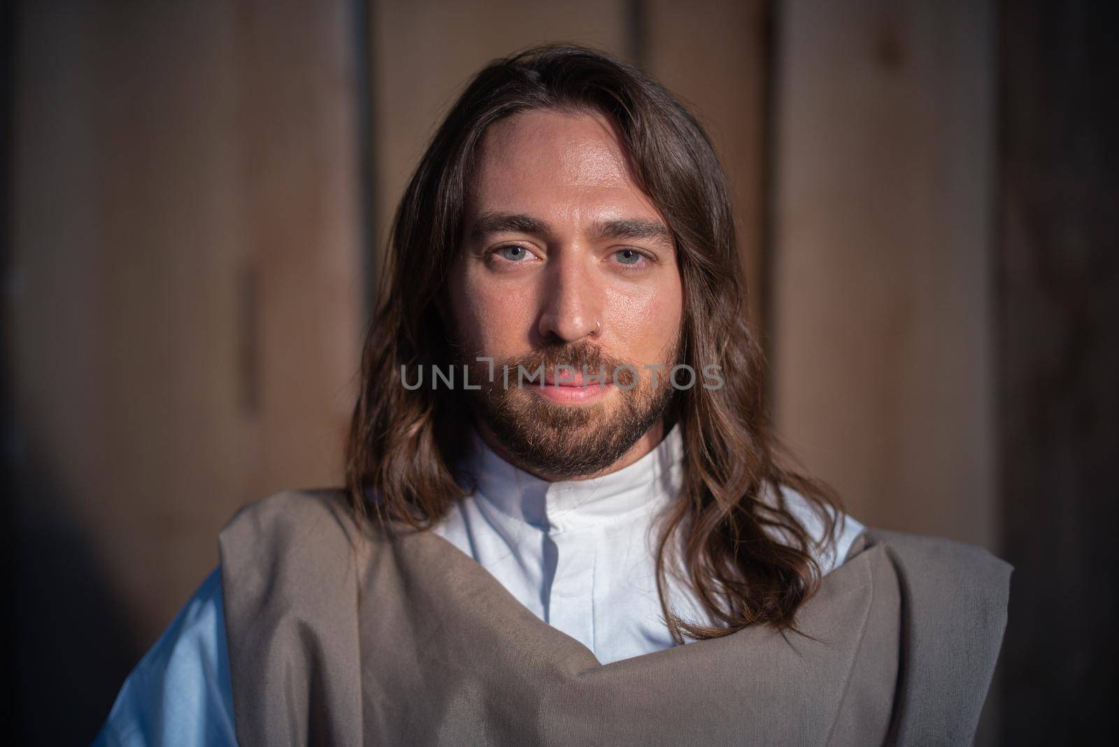 Man representing the biblical character of Joseph facing the camera with serene looking in a crib