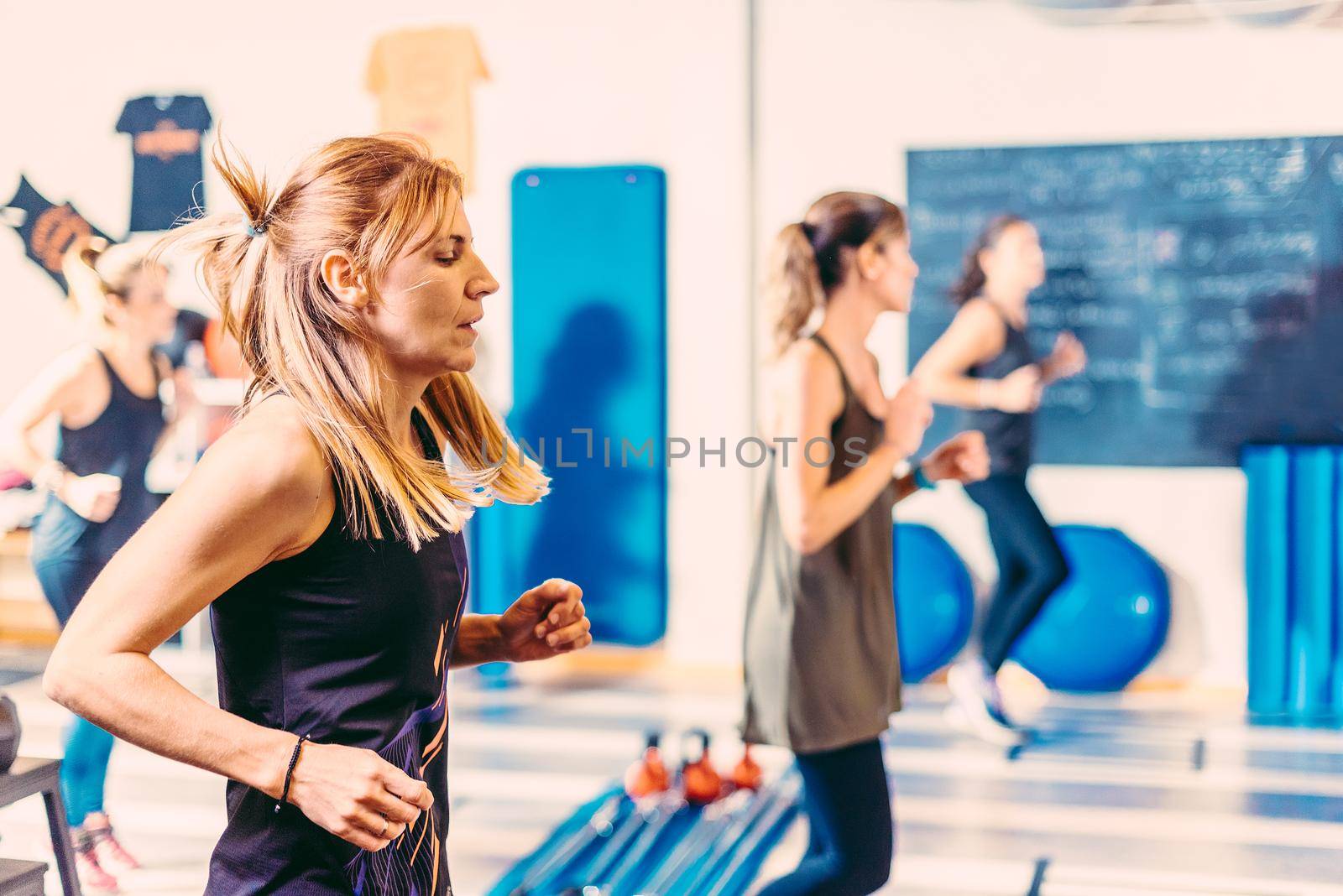 Close up of women doing aerobic exercises in health club by ivanmoreno