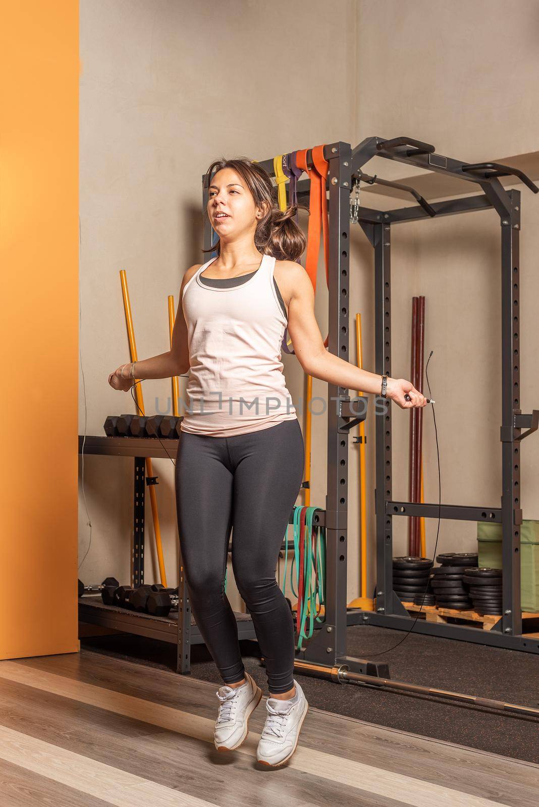 Sportswoman doing jump rope exercise in gym. Concept of exercise with equipment in gym.