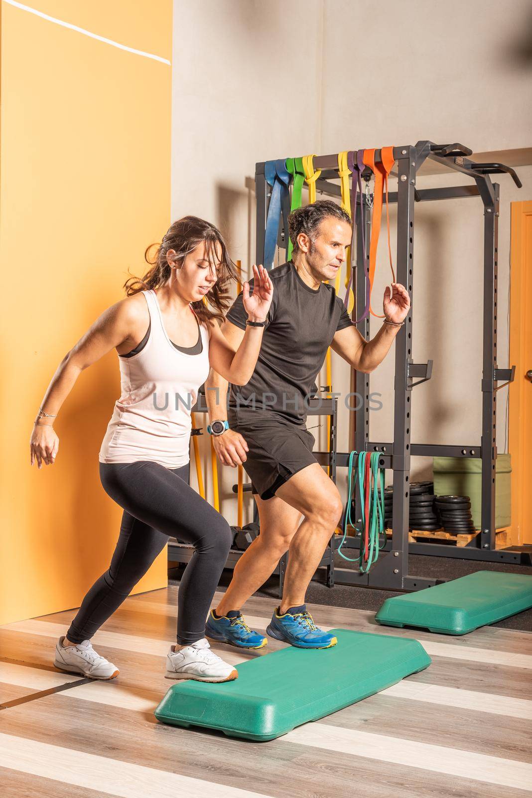 Athlete woman and man doing step up jumps in health club by ivanmoreno