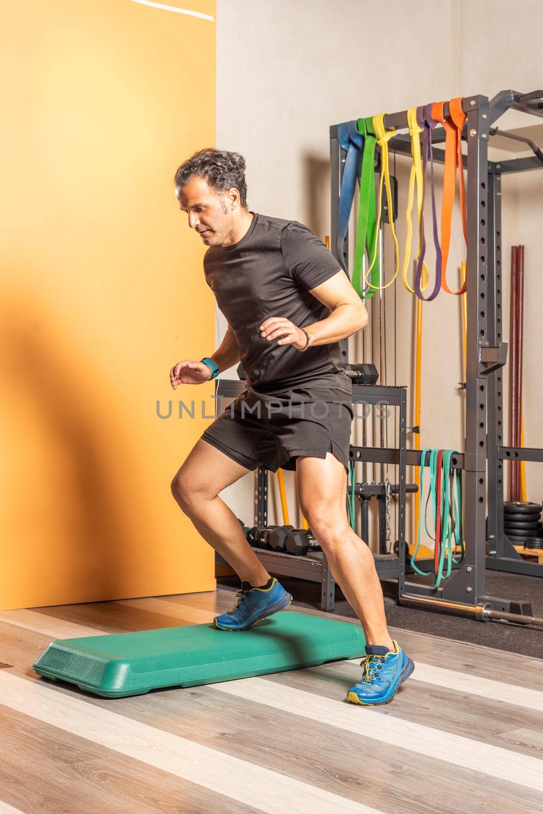 Sportsman doing lateral step up jumps in health club. Concept of exercises with equipment in health club.