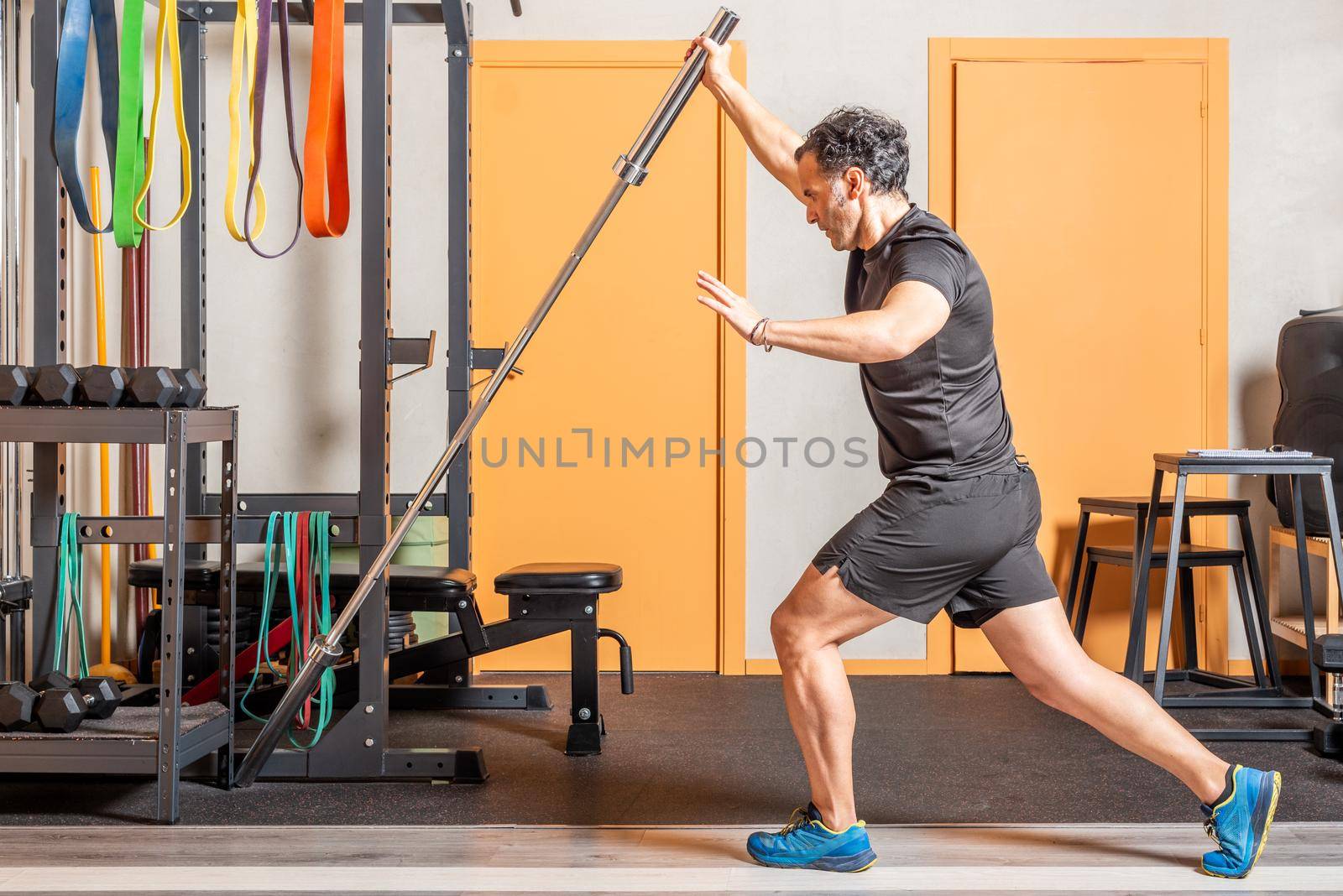 Athlete man doing standing exercise with bar in gym. Concept of exercise with equipment in gym.