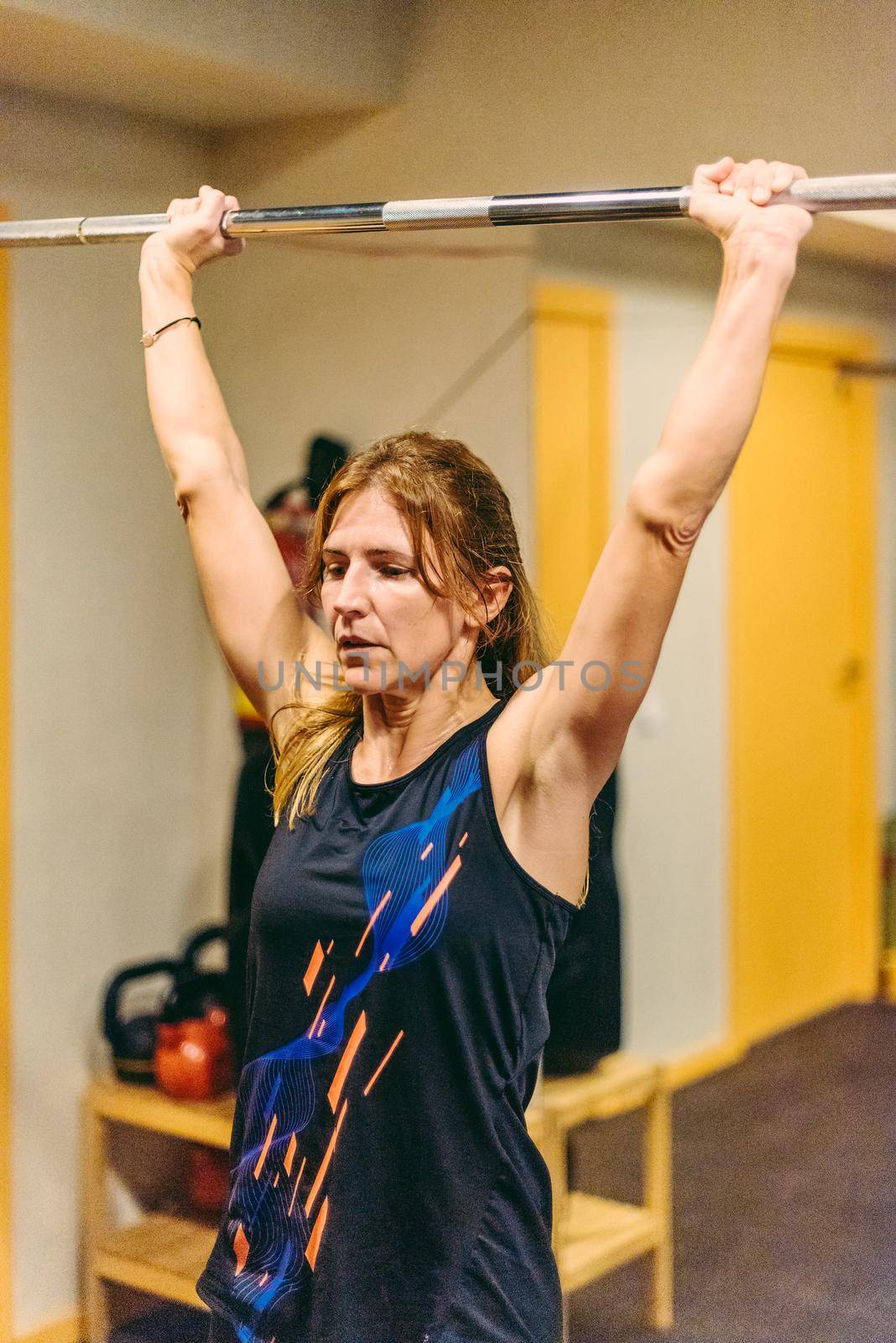Athlete woman doing press exercise with bar in the gym by ivanmoreno