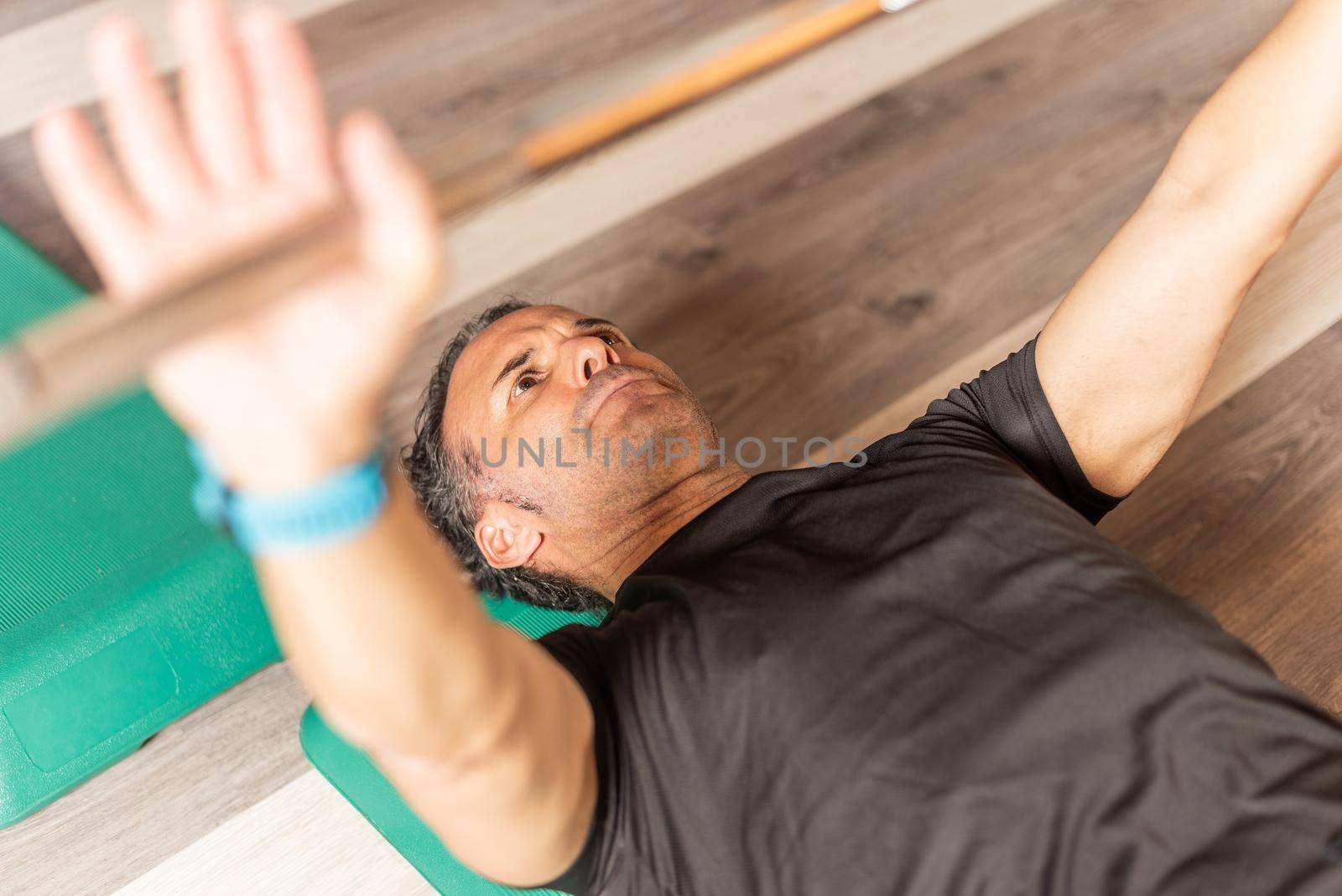 Cropped front view of a sportsman doing bench press on step in gym. Concept of exercise with equipment in gym.